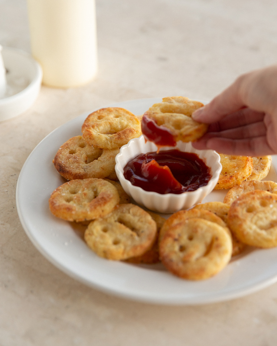 Dipping healthy baked smiley fries in ketchup