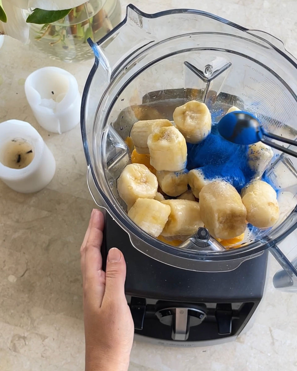 adding blue spirulina in a smoothie jug from a vitamix