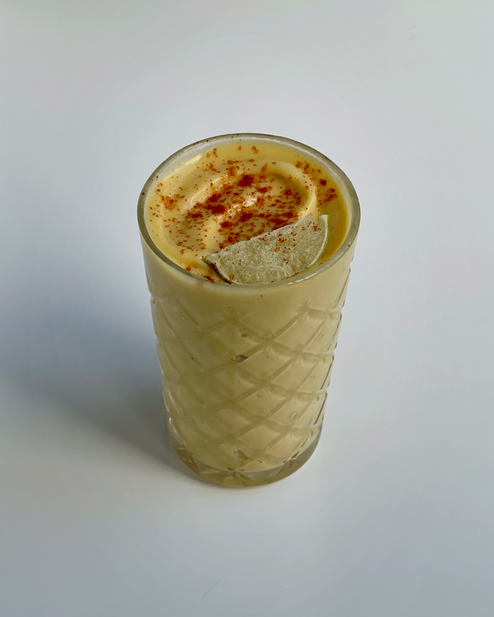 a delicious glass of mango margarita smoothie with a pinch of paprika and a fresh lime